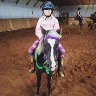 a little girl riding on the back of a horse