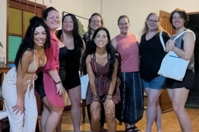 Group of eight people posing together indoors, smiling at the camera.