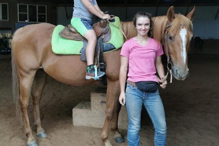 Jessica Hebert riding on the back of a brown horse