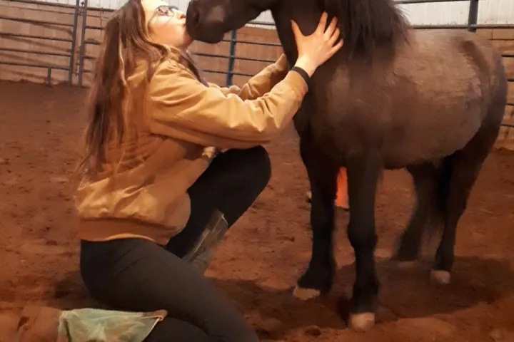 a woman petting a horse