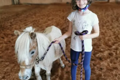 a little girl standing next to a horse