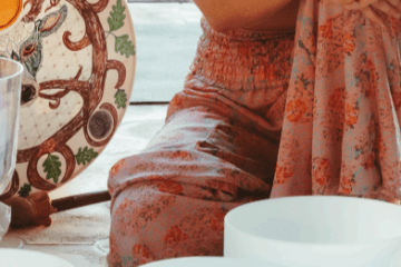 Person in floral attire sitting with sound bowls and decorative plate.