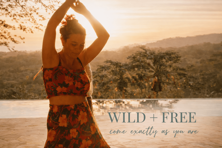 Woman in floral dress dances by a pool at sunset with text 'WILD + FREE'.